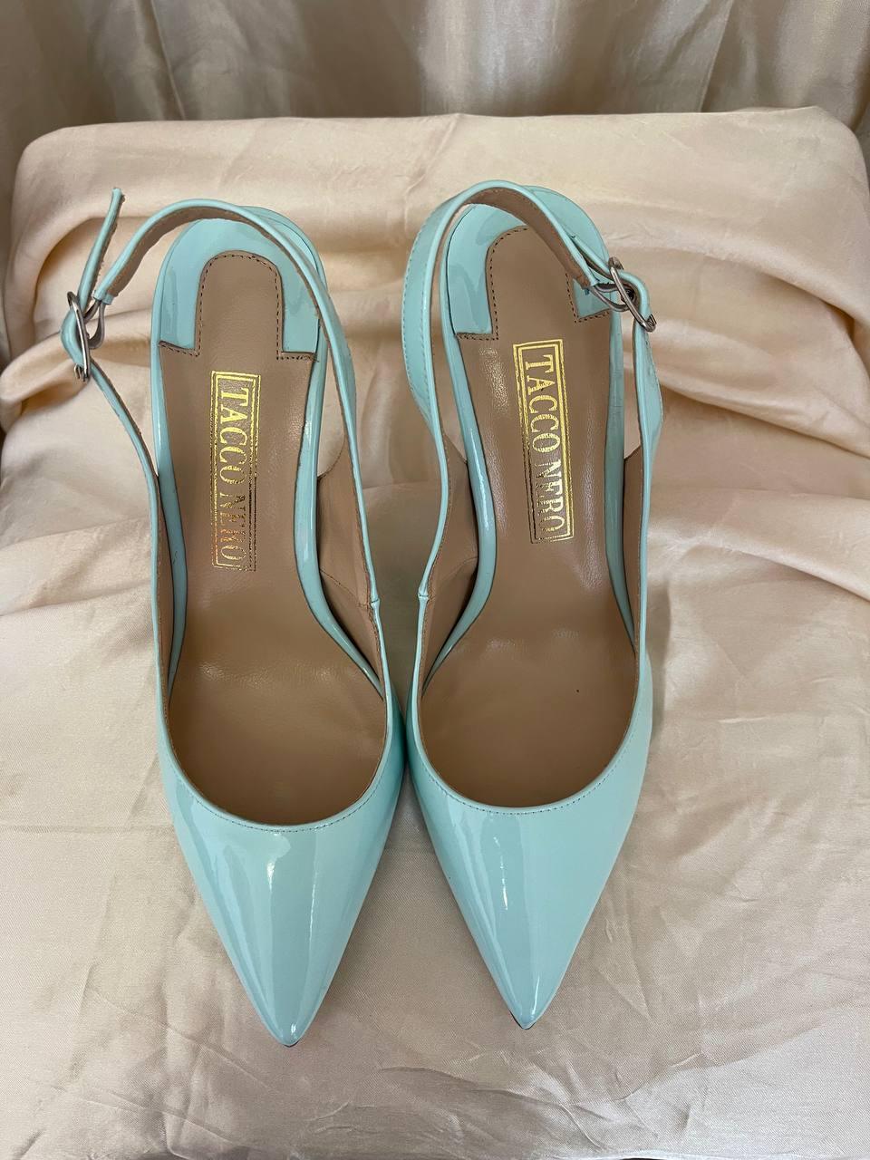 Light blue patent leather pointed toe high heels with ankle strap on beige satin fabric